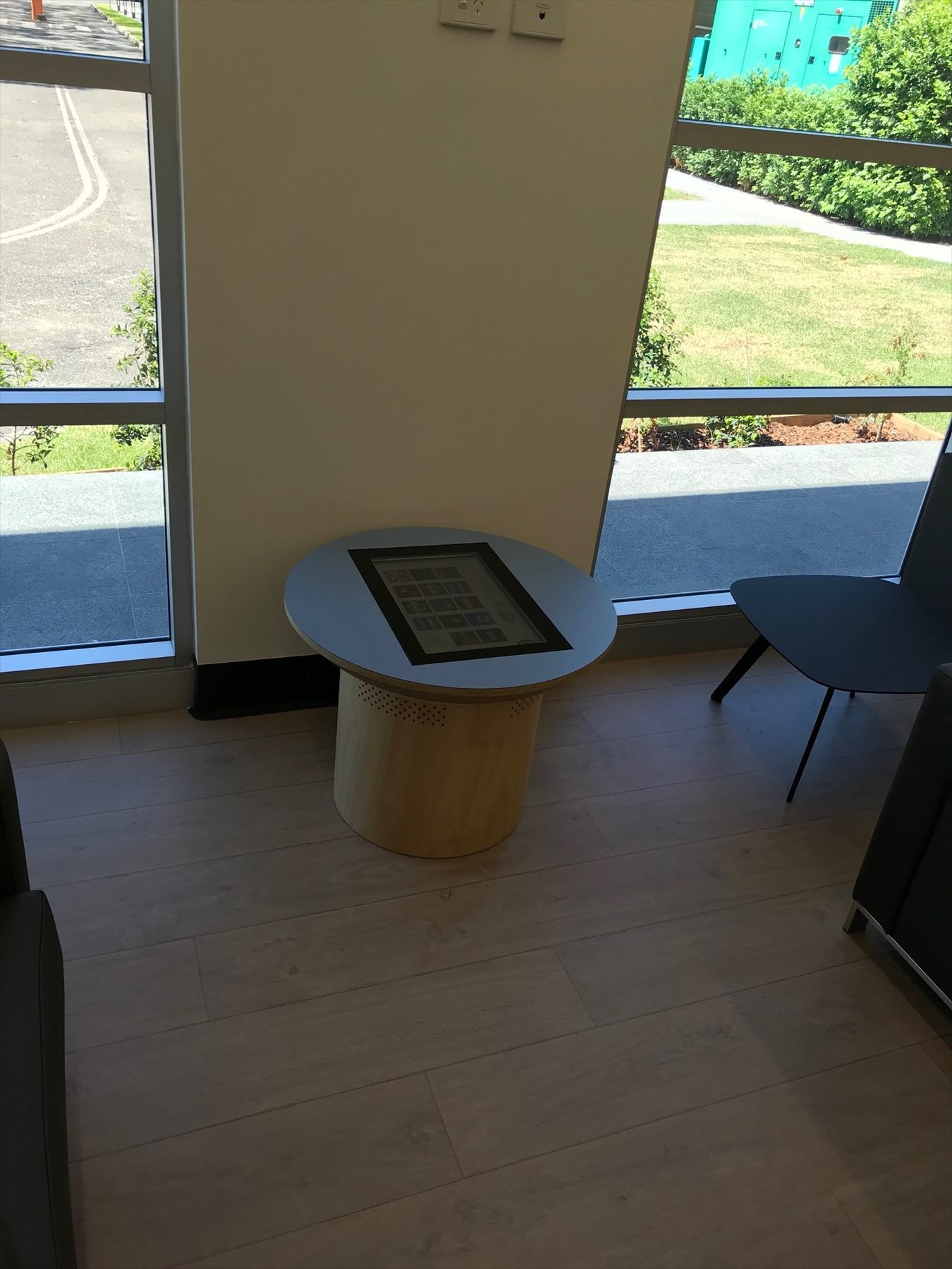 A small table with a touch screen and a chair in a bright hospital room