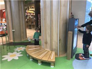 Children using an interactive touch screen built into a wooden tree structure at Chadstone