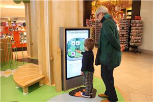 A child and an adult playing a touch screen game in a tree-shaped play structure at Chadstone