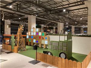 A farm-themed play area with a green tractor, windmill and shape wall at Grand Central Shopping Centre