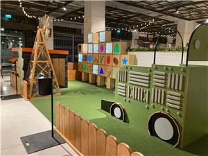 A farm-themed kids play area with a windmill and a green tractor in a shopping centre