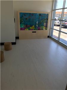 A kids room with a large interactive wall and a round stool