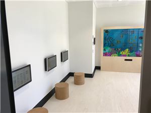 A room with a big interactive underwater wall and two touch screens on the wall