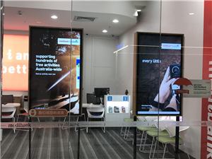 Two portrait digital screens in the window of a Medibank store