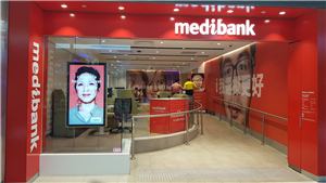 A Medibank store entrance with a portrait digital screen and feature wall