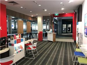 The entrance to a Medibank store with brochures and a red feature wall