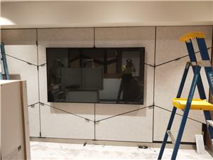 A screen being installed on a wall in a new Medibank store with a ladder in front