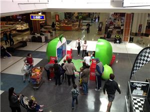 An overhead view of a giant green apple display with shoppers in a shopping centre