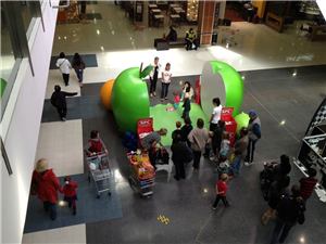 Families with shopping trolleys gathered around the SPC giant apple game