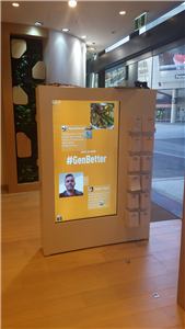 A timber wayfinding unit with a touch screen showing a #GenBetter message