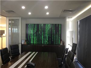 A boardroom with a video wall showing green digital code
