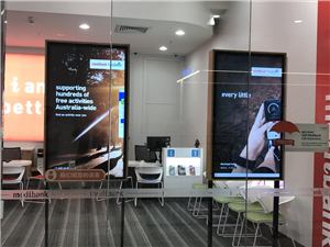Two portrait digital screens in the window of a Medibank store