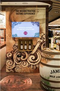 A Jameson tasting display with a screen and barrel in an airport store
