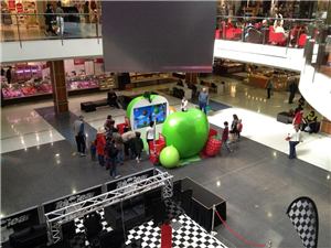 An overhead view of a giant green apple display and shoppers in a shopping centre