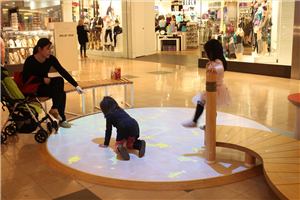 Children playing on a circular interactive floor in a shopping centre