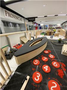 A play area under construction with a boat-shaped timber play piece and number discs