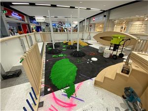A play area under construction with a green leaf shape and timber steps