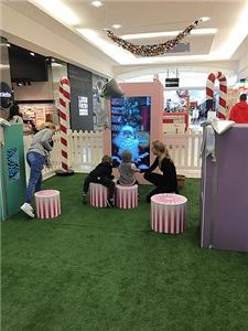 A Santa video booth in a pink gift box with children at Northland