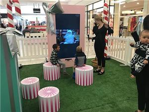 Children and a helper at a live Santa video booth at Northland