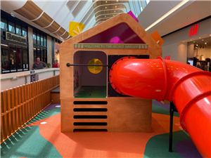 The Secret Garden timber house with a red tube slide at Grand Central Shopping Centre