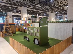 A green farm truck play structure behind a picket fence at Grand Central Shopping Centre