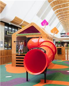 A child at the top of the red tube slide at the Secret Garden play house