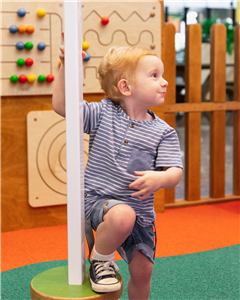A boy playing at a play wall panel with a bead maze