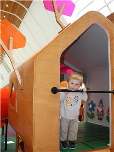 A toddler standing in the doorway of the Secret Garden house