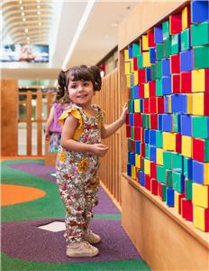 A girl at a colourful block wall in the Grand Central play space